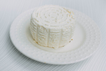 homemade cheese on a white plate on a white background.Adyghe cheese from milk. Home cheese making