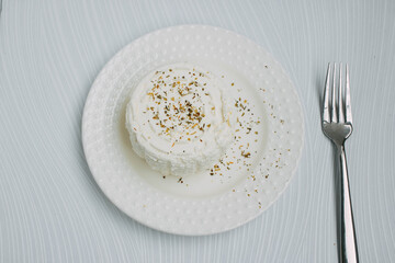 Adyghe homemade cheese on a plate with spices with a fork