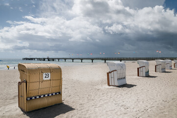 Empty beach chairs on the Baltic Sea beach and pier with the flags of German constituent states and cities. Grossenbrode, Schleswig- Holstein, Germany