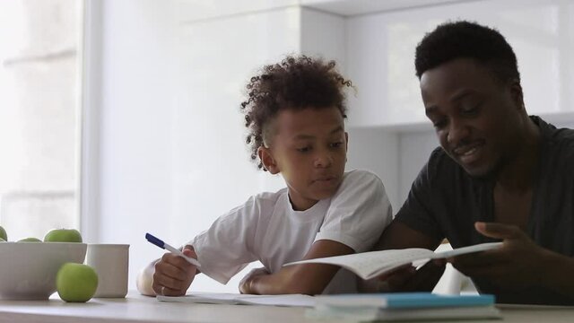 boy child son is shocked, surprised when sees homework Spbi. doing school task at home with dad. father helping with education. concept support, notebook, writing. afro and mixed family