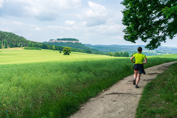 Fototapeta premium Woman running with view at the Fortress Königstein in the Saxon Switzerland