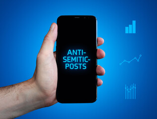 Anti-semitic-posts. Hand holds phone (cell phone). Word on display. Charts on blue background....