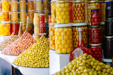 Glass jars with olives and piles of olives in a market