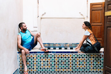 Couple sitting and looking at each other on a wall made of ceramic mosaic