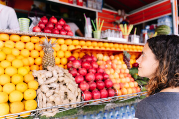 Selective focus on a woman facing a fruit juice ststrawand at a market