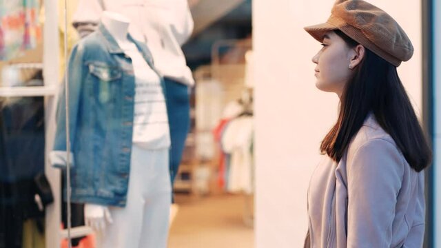 young attractive woman walks around mall, stops near storefront and thinks what to buy