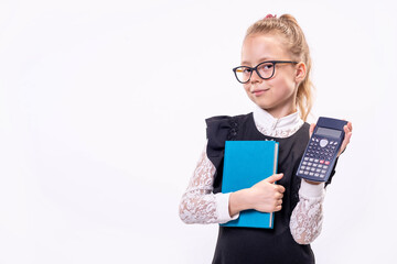 Little schoolgirl in glasses stands on a white background and holds a book and a calculator.