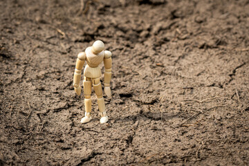 Wooden man standing on soil dry land