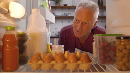 Mature man taking ingredients from fridge for cooking meal