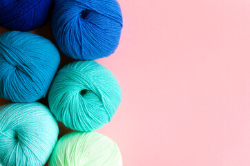 Acrylic balls of yarn in blue-green shades on a pink background. Nuance color combination.