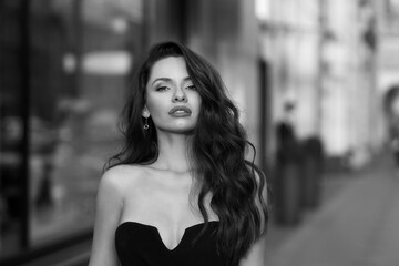 Closeup outdoor face portrait of young beautiful woman with long wavy hair looking at you or in camera