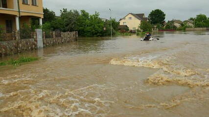 Flood survivors sitting in inflatable boat rescued by pair of rescuers. Family saved from flooded area or town. People natural disaster. Wait for evacuation mororboat on overflowing street as tens