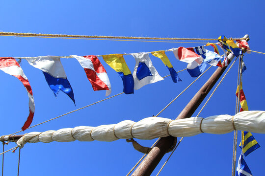 Sea signal flags mounted on the mast against the blue sky, taken close-up. Ship's flags fluttering in the sky. Signals, Morse code. Flagpole.