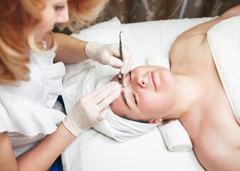 Obraz na płótnie Canvas Cosmetologist squeezes acne. Procedure for cleansing problem skin