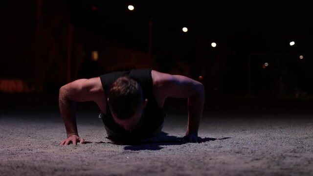 Man training outdoor at night. He doing push ups