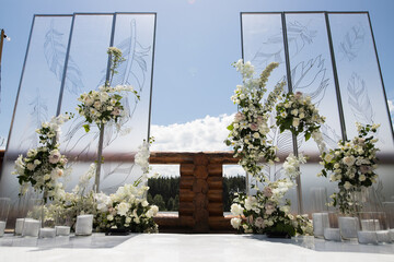 Wedding ceremony with white transparent screens and fresh white flowers and candles
