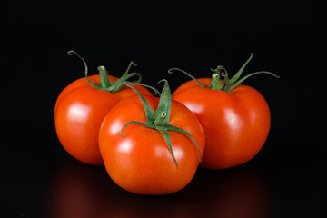 Drei saftige reife rote Tomaten auf einem neutralen schwarzen / dunklen Hintergrund