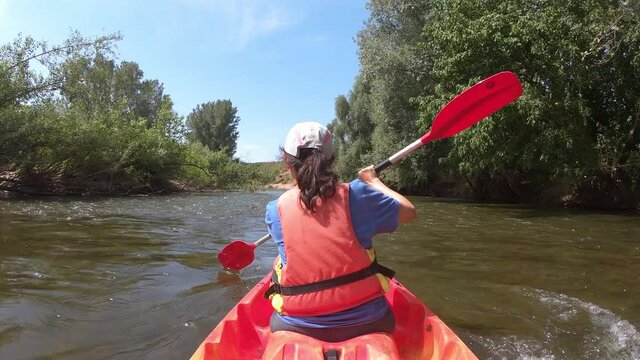Young hispanic woman kayaking on the river Ter on a summer sunny day,Catalonia of Spain