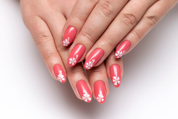 Coral, peach, pink manicure with painted white flowers on all nails close-up on a white background....