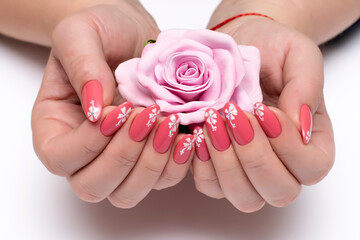 Coral, peach, pink manicure with painted white flowers on all nails close-up on a white background....