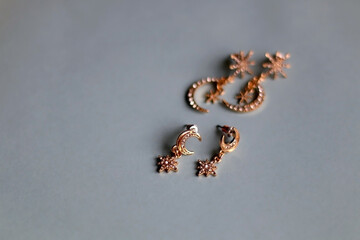 Two pairs of gold earrings on pale blue background. Selective focus.