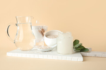 Healthy rice water with cosmetic supplies on color background