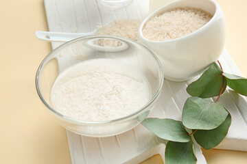 Bowl of rice water on color background