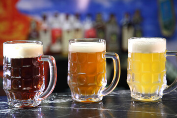 Glasses with different sorts of craft beer. Red, bronze and white beer in beer glasses on the bar. Glasses of light and dark beer on a pub background. 