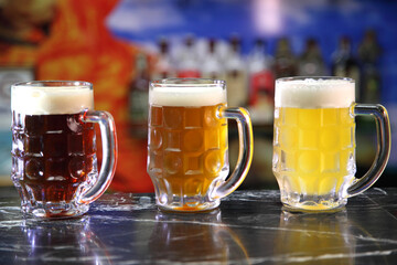 Glasses with different sorts of craft beer. Red, bronze and white beer in beer glasses on the bar. Glasses of light and dark beer on a pub background. 
