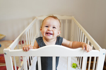 Little pretty girl in a white crib laughing and smiling