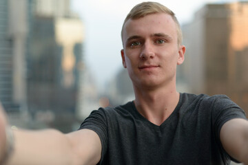 Portrait of young man with blond hair against view of the city