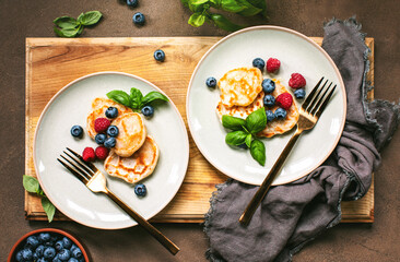 Pancakes with summer berries served for breakfast, overhead view on a table setting
