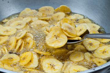 Kerala banana chips  popular deep fried snack traditional South Indian tea time snack on banana leaf, Kerala India. Frying chips in coconut oil on Onam, Vishu, Diwali/Deepawali, Ramzan, Eid. 
