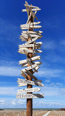 Creative, wooden signpost on the beach against the blue sky. Pointer with white tablets.