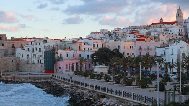 Beautiful sunset on Vieste town with embankment Park and Church of San Francesco, Italy, Europe. Stormy wether on Adriatic sea. Full HD video (High Definition).