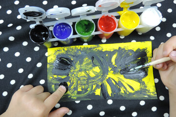 gouache paints of different colors and children's hands draw a picture, children's creativity