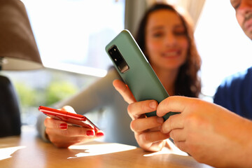 Man and woman are sitting in cafe and looking at smartphones. Trust relationship between man and woman concept