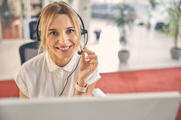 Cheerful young woman in headset working in office