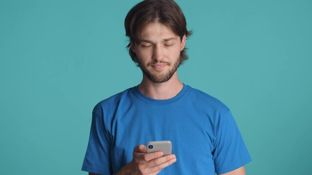 Attractive serious bearded waving no gesture while guy using smartphone over colorful background