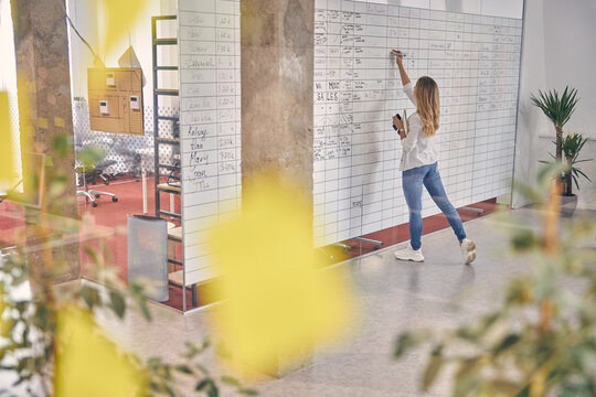 Female Office Worker Writing On Planner Task Board