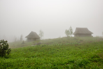 Stare drewniane chaty pasterzy spowite w gęstej mgle. Tatry, Polska © Kamil_k2p