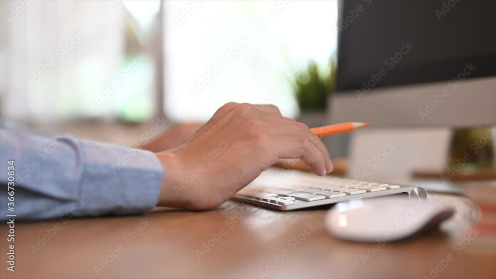 Aufkleber cropped image smart man works with a computer while sitting at the wooden working desk.