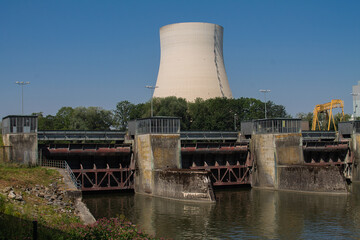 Obraz premium Three locks of a hydropower plant with a machine house. And a cooling tower of a nuclear power plant in the background.