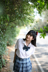 Naklejka premium Asian school girl walking and looking in urban city with tree background