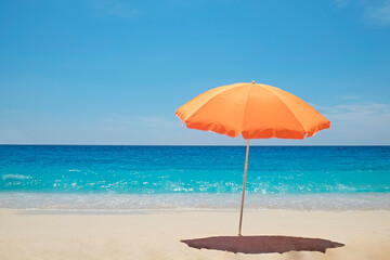 Single orange umbrella on a perfect beach with clean golden sand and clear turquoise water on a...