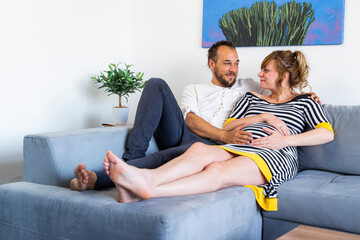 A young and embracing married couple is lying on the couch