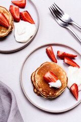 Homemade pancakes with strawberry and whipped cream (chantilly) on grey concrete background. Selective focus