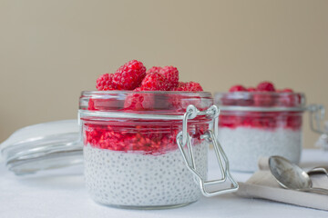 Chia pudding with coconut milk and fresh raspberries in glass jars. Healthy vegan breakfast  Clean eating concept.