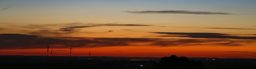 Beautiful sunset with city lights and windmills