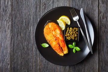 fried juicy salmon steak on a black plate
